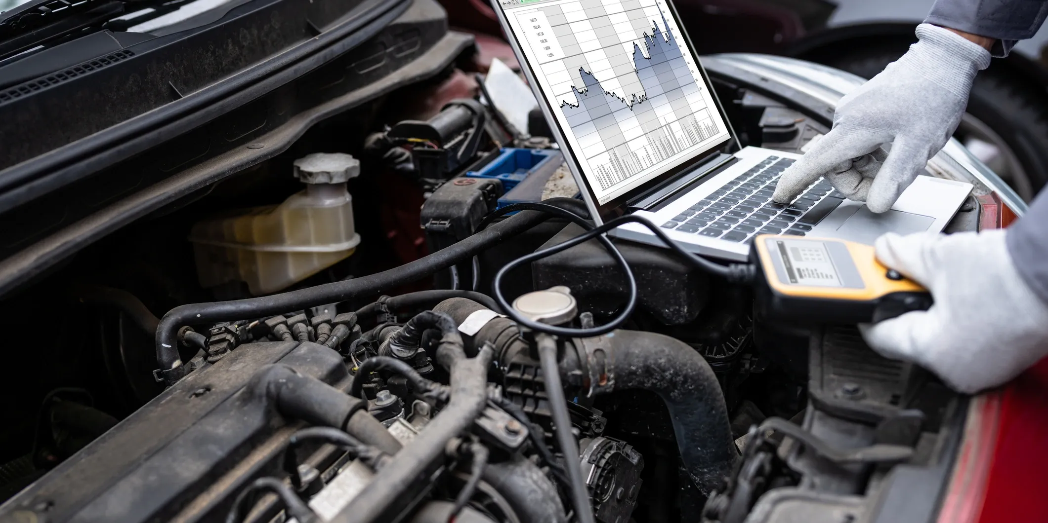 cr=t_12 Mechanic wearing gloves uses a diagnostic scanner and laptop to read engine data while inspecting a car engine at a family-owned auto repair shop in Tucker, GA