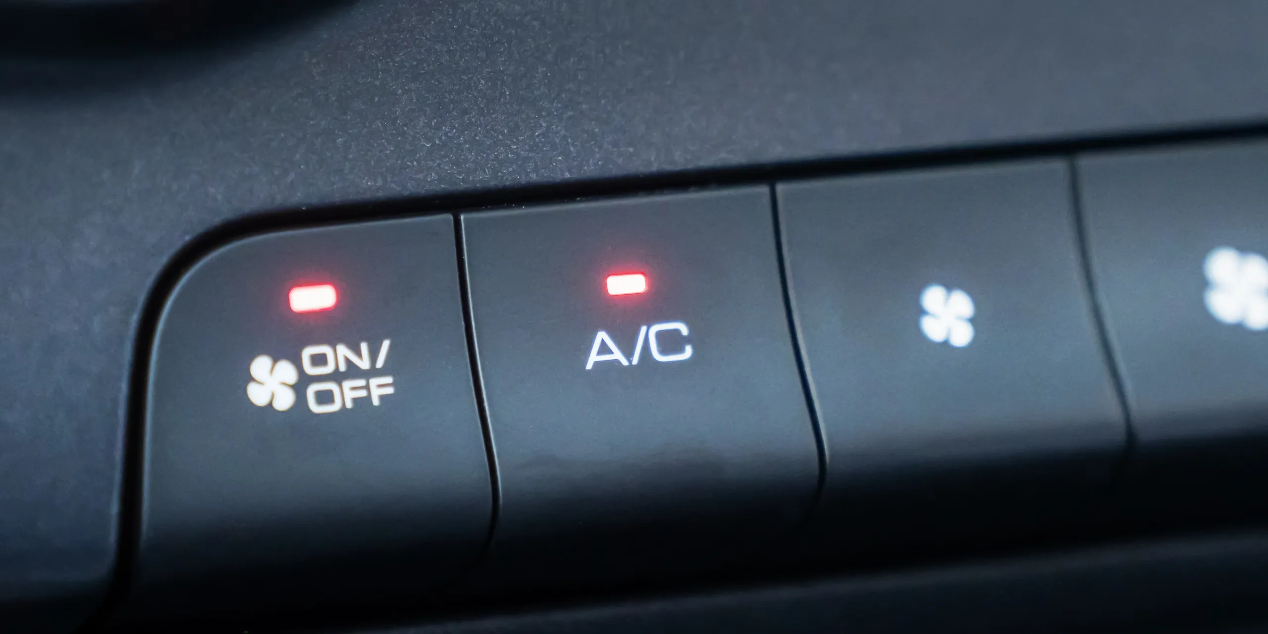 cr=t_12 Close-up of a vehicle dashboard climate control panel showing illuminated A/C button and fan on/off icon, illustrating auto air conditioning and HVAC repair services for a Tucker, GA family-owned auto shop